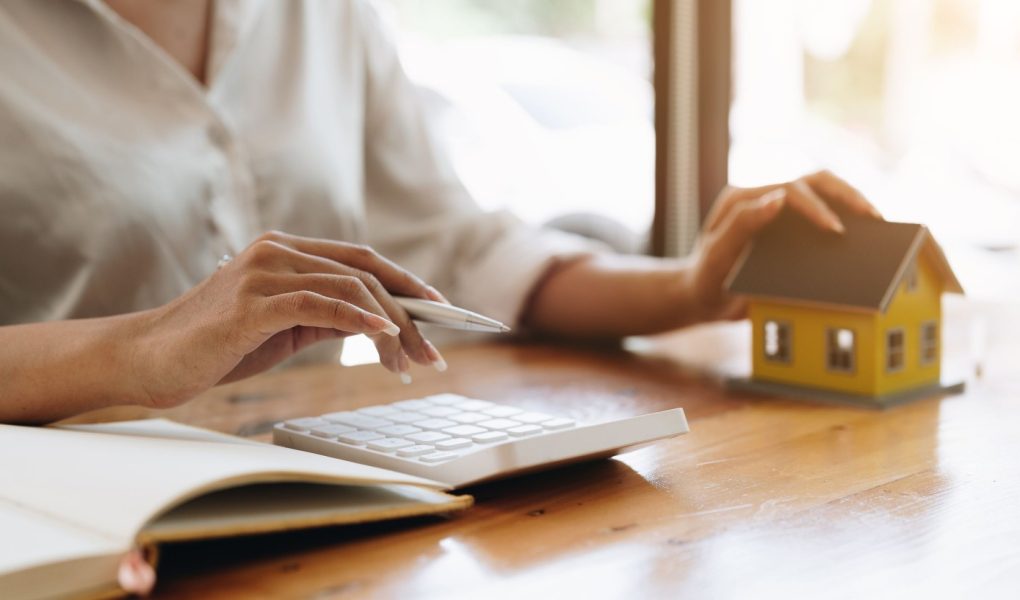 Zbliżenie ręki księgowego obliczającego odsetki, podatki i zyski z inwestycji w nieruchomości i kupno domu