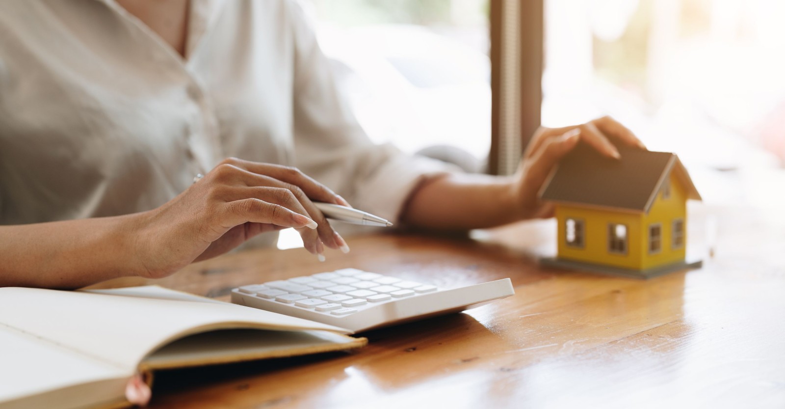Zbliżenie ręki księgowego obliczającego odsetki, podatki i zyski z inwestycji w nieruchomości i kupno domu