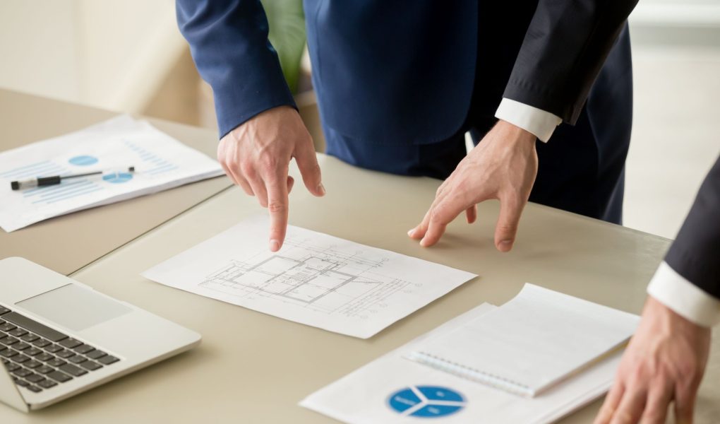 Widok z bliska biznesmenów omawiających plan budowy, szacowanie wartości nieruchomości, analizowanie rynku nieruchomości za pomocą statystyk infograficznych, wycena domu, inwestycja budowlana, wycena domu