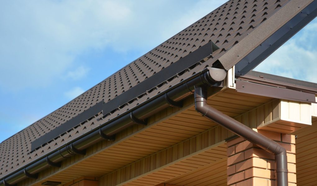 Budowa nowoczesnego domu z metalowym narożnikiem dachowym, systemem rynnowym i zabezpieczeniem dachu przed śniegiem. Osłony przeciwśniegowe dachu: Materiały budowlane