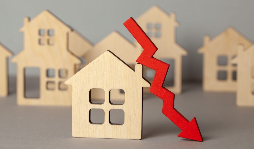 Strzał w dół i wiele domów. Spadające ceny nieruchomości na rynku. Kupno i sprzedaż domu.
