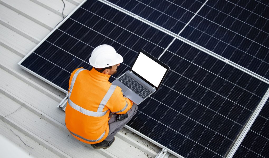 Pracownik zajmujący się energią słoneczną instaluje panele fotowoltaiczne na dachu.