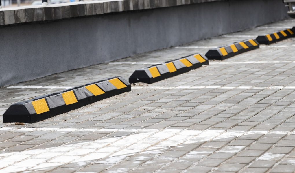 Pusty parking w dzielnicy mieszkalnej z żółtymi ogranicznikami parkowania dla samochodów. zbliżenie. Ogranicznik parkowania