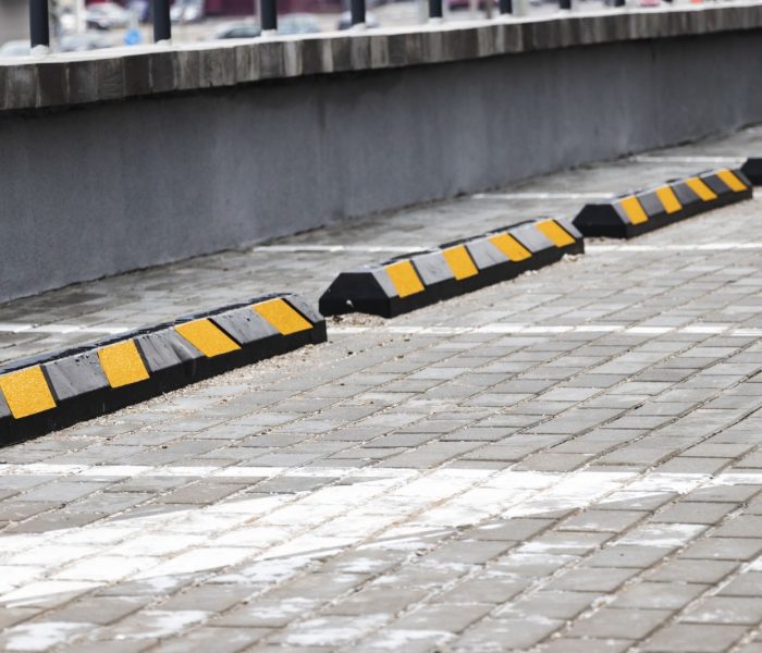 Pusty parking w dzielnicy mieszkalnej z żółtymi ogranicznikami parkowania dla samochodów. zbliżenie. Ogranicznik parkowania