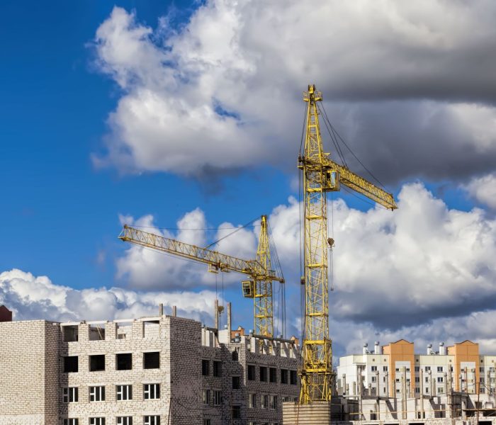 budowa nowego wielokondygnacyjnego budynku mieszkalnego z bloków żelbetowych, plac budowy, obszar działalności związanej z budową i remontem, duże dźwigi budowlane