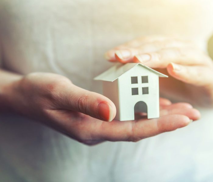 Kobieta ręce trzymając mały miniaturowy biały domek zabawka. Ubezpieczenie nieruchomości hipotecznych marzenie o przeprowadzce do domu i koncepcja nieruchomości