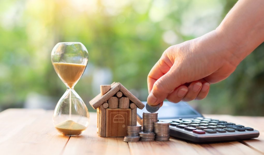 Ręka wkładająca monety do rzędu monet. Nieruchomości lub rozwoju nieruchomości. Plan oszczędzania monet na zakup domu pomysły na nieruchomości hipoteczne i inwestycje w nieruchomości na zakup domu.