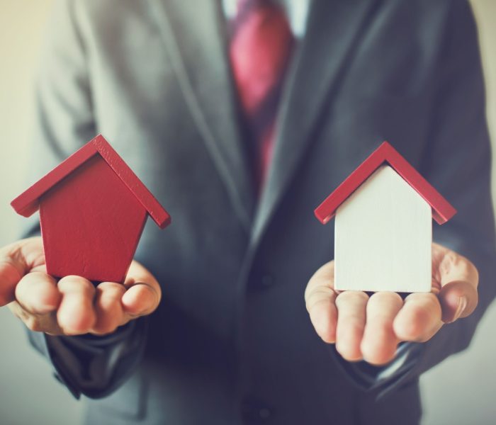 Biznesmen posiadający dwa domy i nie może zdecydować się na wybór odpowiedniego domu.