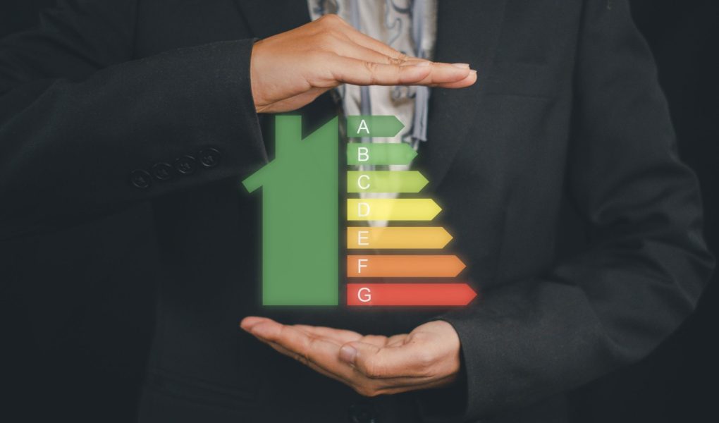 Kobieta biznesu trzymająca ikonę domu, obraz skali efektywności energetycznej na wirtualnym ekranie, koncepcja ekologicznego i bioenergetycznego domu. Klasa energetyczna.