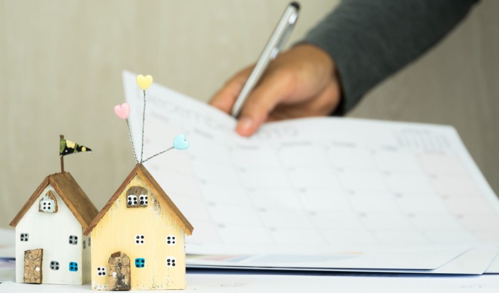 Podpis ludzi biznesu w dokumentach wykres sprawdzający dokument kalendarza w projekcie inwestycji w nieruchomości na biurku. Raport sprzedaży w marketingu hipotecznym w koncepcji nieruchomości. Dwa domy w centrum uwagi