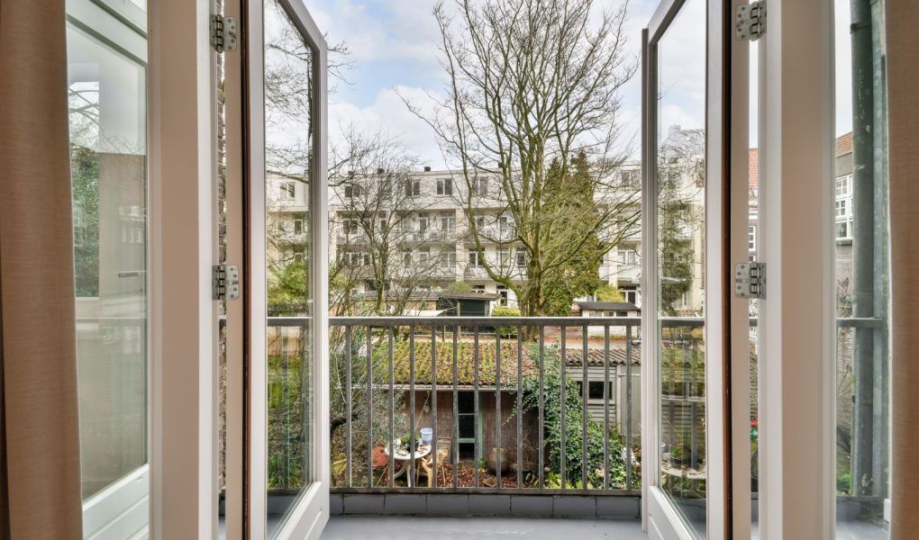 Dostęp do przytulnego balkonu nowoczesnego domu z drewnianymi drzwiami i metalowym ogrodzeniem