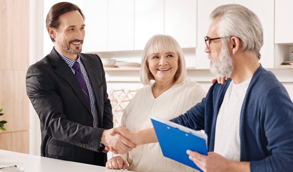 Spotkanie z przyszłymi właścicielami domu. Zachwycony, doświadczony, pozytywny agent nieruchomości spotykający się ze starą parą klientów podczas uścisku dłoni i prezentacji umowy