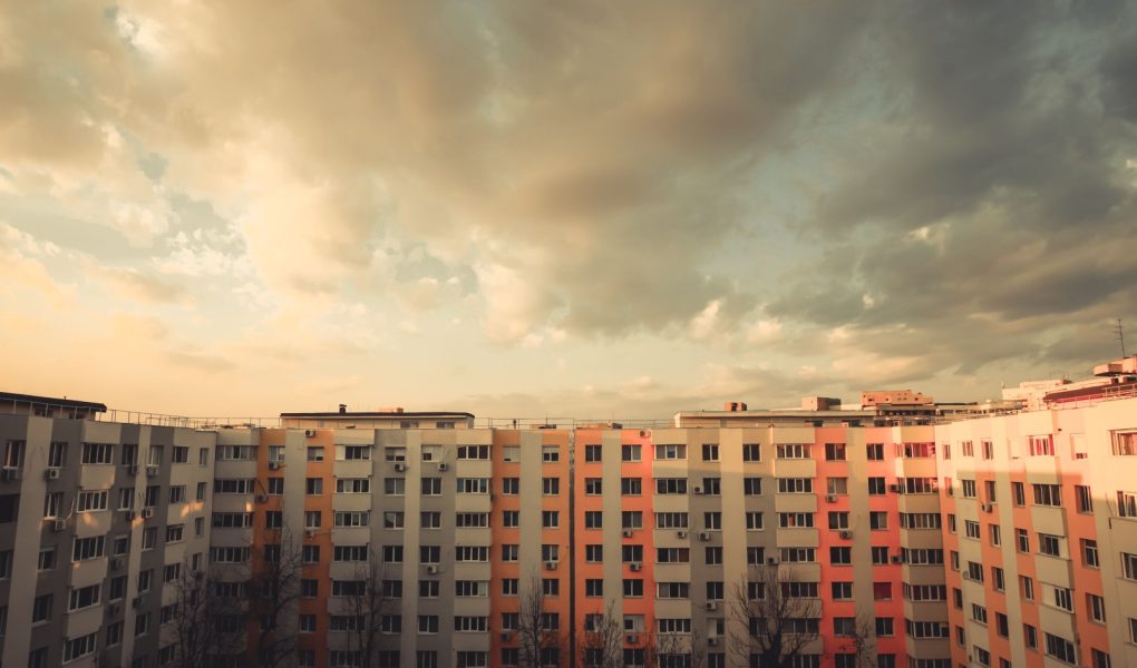 Kolorowy obraz niektórych mieszkań w bloku o zachodzie słońca.