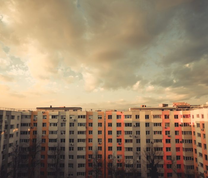 Kolorowy obraz niektórych mieszkań w bloku o zachodzie słońca.