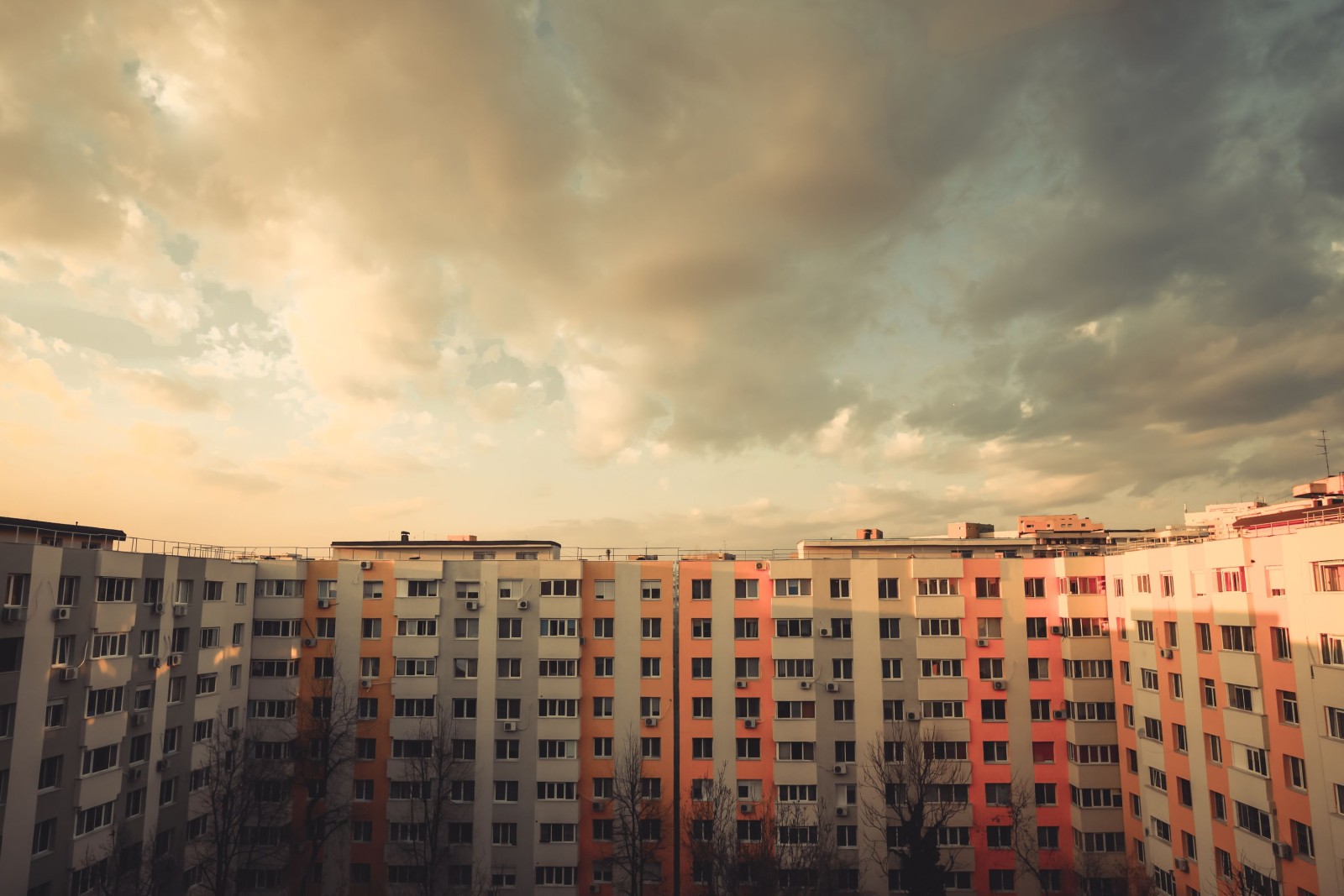 Kolorowy obraz niektórych mieszkań w bloku o zachodzie słońca.