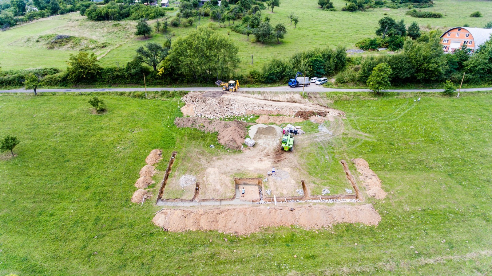 Plac budowy. Budowa betonowego fundamentu pod nowy dom. Wlewanie mokrego cementu. Betoniarka. Maszyna do transportu cementu. Piękna letnia przyroda.