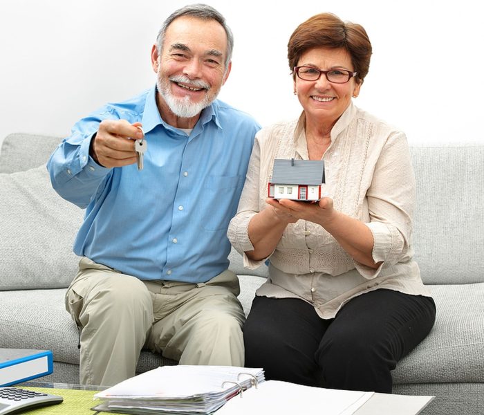 Szczęśliwa para seniorów trzymająca mały domek i klucze w rękach