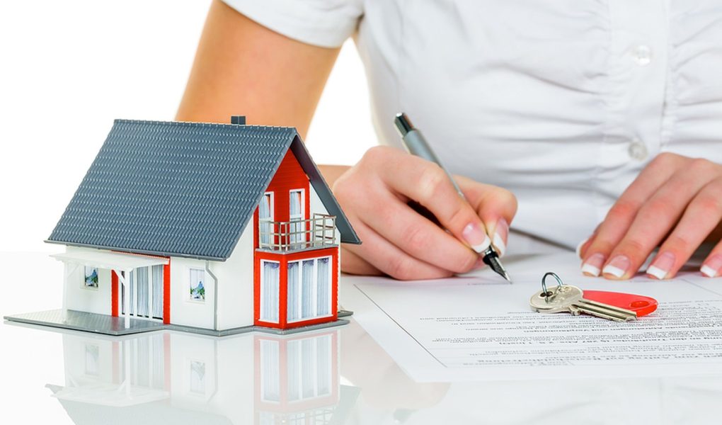 Kobieta podpisuje umowę kupna domu z agentem nieruchomości.