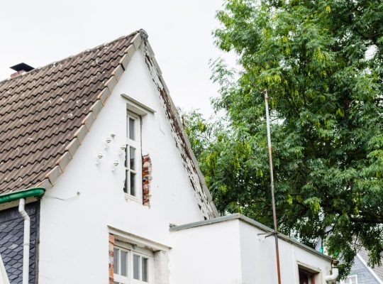 Widok fasady domu przeznaczonego do przebudowy. Nowe okna są już zamontowane.