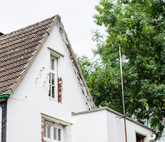 Widok fasady domu przeznaczonego do przebudowy. Nowe okna są już zamontowane.