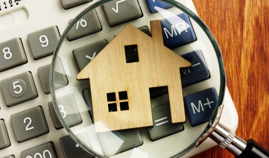Wartość domu. Model domu, kalkulator i szkło powiększające.