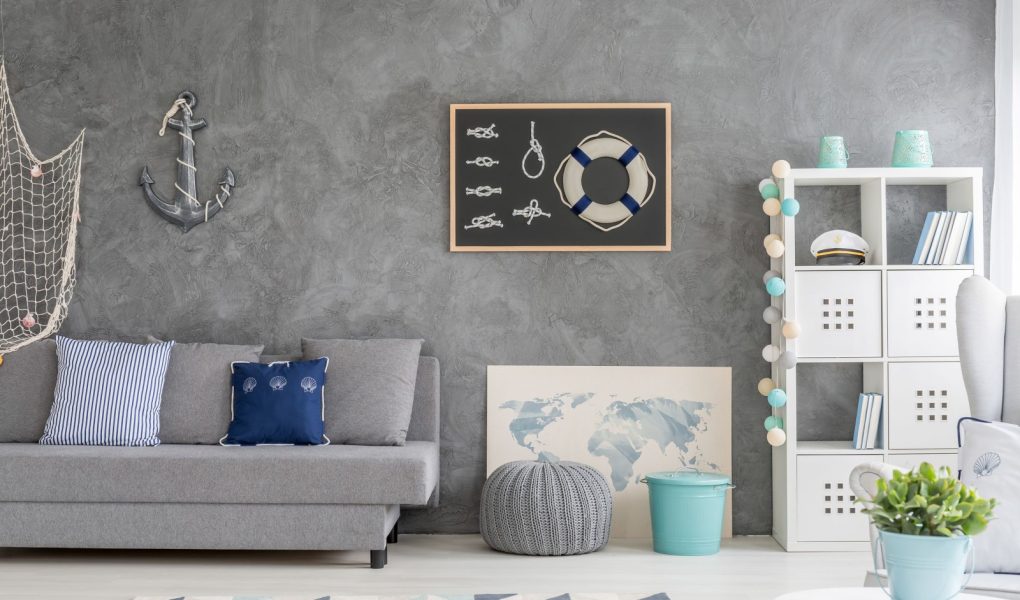Szare wnętrze domu z marynistyczną dekoracją ścienną, sofą, dywanem i białym schowkiem