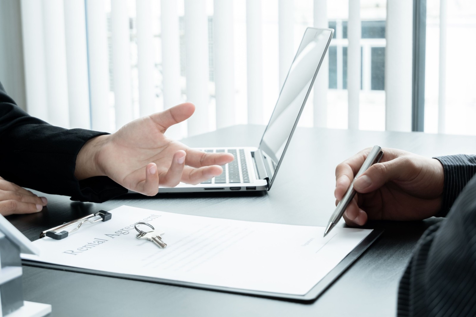 Agent nieruchomości z modelem domu rozmawia z klientami na temat wynajmu domu i zakupu ubezpieczenia domu oraz zawarcia umowy po zakończeniu formalnych negocjacji.