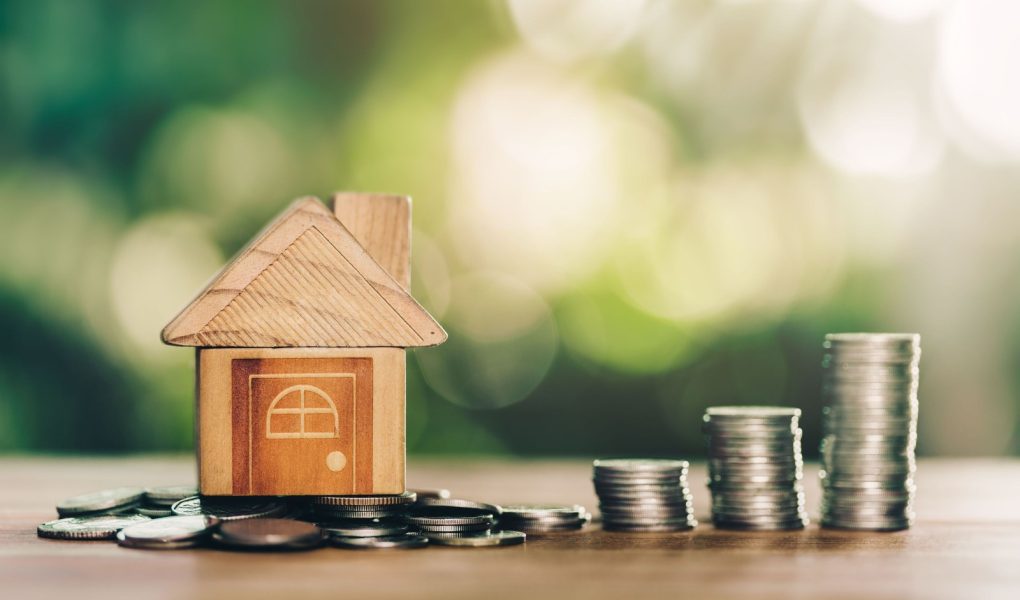 Dom umieszczony na monetach i monetach umieszczonych na drewnianym stole to drabina. planowanie oszczędności w monetach na zakup domu koncepcja koncepcji drabiny nieruchomości, kredytu hipotecznego i inwestycji w nieruchomości.