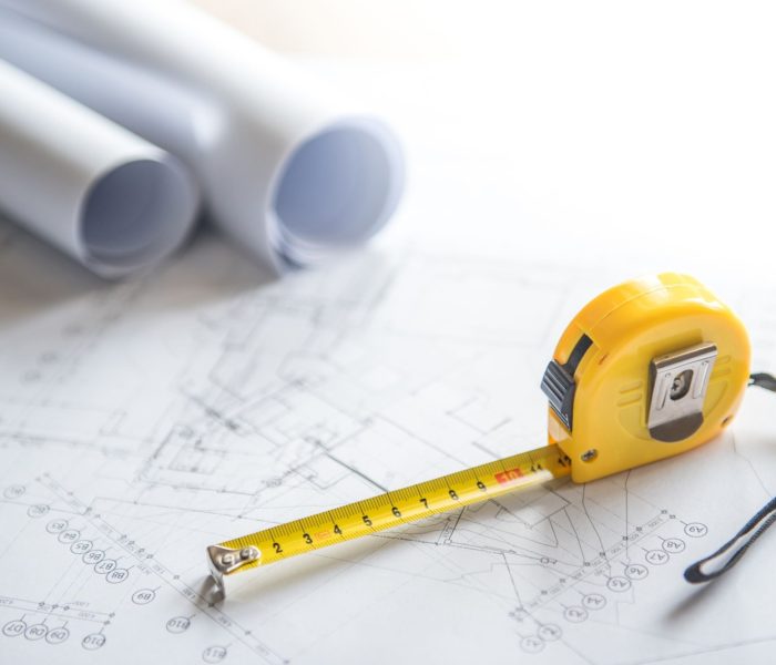 rysunek architektoniczny plan projektu domu rolki i żółta taśma miernicza (taśma miernicza) na stole roboczym koncepcje branży budowlanej