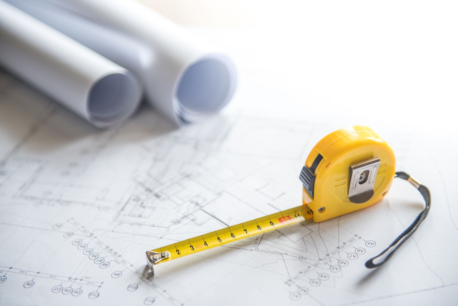 rysunek architektoniczny plan projektu domu rolki i żółta taśma miernicza (taśma miernicza) na stole roboczym koncepcje branży budowlanej