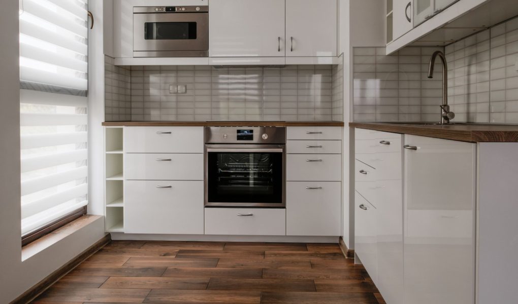 Nowe umeblowane mieszkanie mała biała kuchnia z oknem.