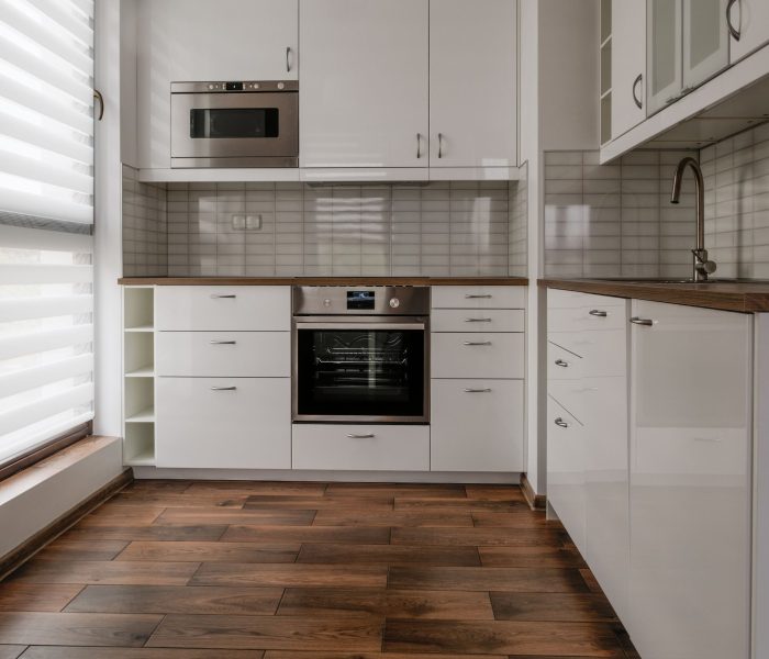 Nowe umeblowane mieszkanie mała biała kuchnia z oknem.