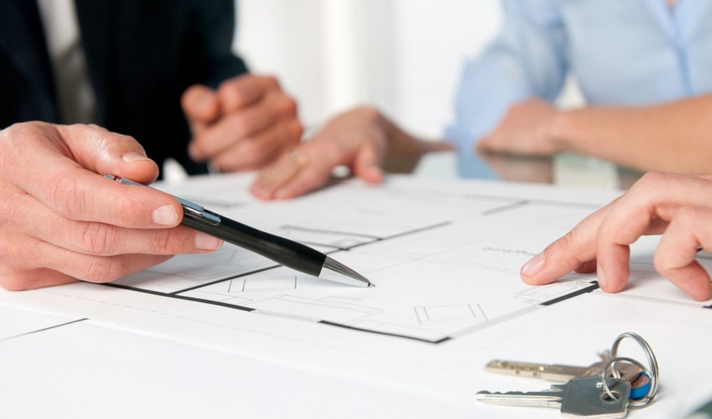Zbliżenie na klucze do nowego domu i plan domu podczas rozmowy z agentem nieruchomości