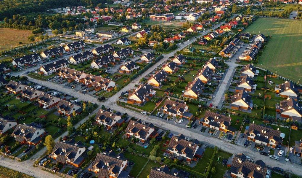 Widok z lotu ptaka na podmiejską dzielnicę, dzielnicę mieszkaniową z budynkami i ulicami w małym europejskim miasteczku o zachodzie słońca