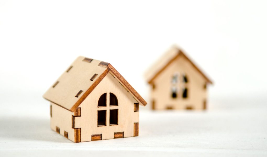 Dwa małe drewniane domy na czarnym tle, różowe serca między nimi, koncepcja szczęścia rodzinnego, kupno domu