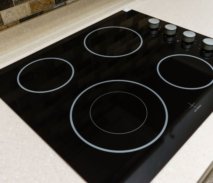 Nowoczesna czarna kuchenka indukcyjna lub wbudowana płyta grzewcza z ceramicznym blatem w białym wnętrzu kuchni