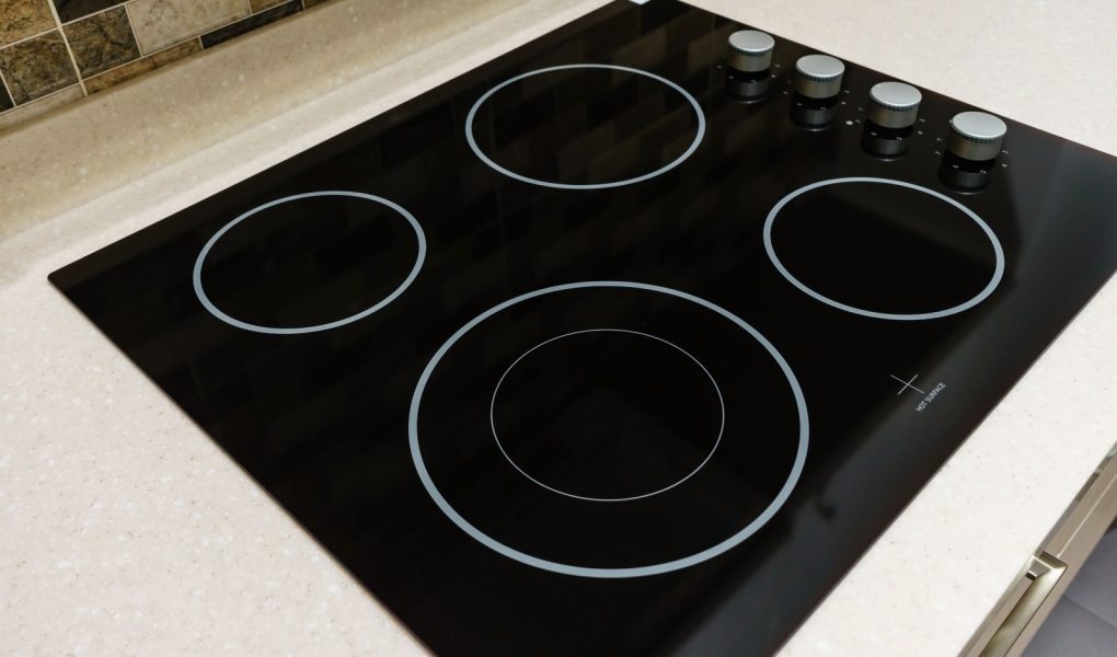 Nowoczesna czarna kuchenka indukcyjna lub wbudowana płyta grzewcza z ceramicznym blatem w białym wnętrzu kuchni