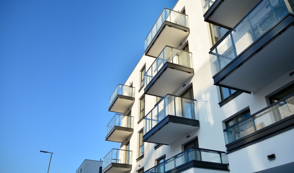 Fasada nowoczesnego apartamentowca w słoneczny dzień. Nowoczesne budynki mieszkalne z ogromnymi oknami i balkonami.