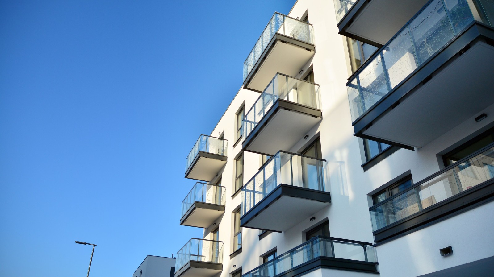 Fasada nowoczesnego apartamentowca w słoneczny dzień. Nowoczesne budynki mieszkalne z ogromnymi oknami i balkonami.