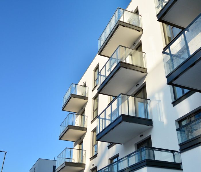 Fasada nowoczesnego apartamentowca w słoneczny dzień. Nowoczesne budynki mieszkalne z ogromnymi oknami i balkonami.